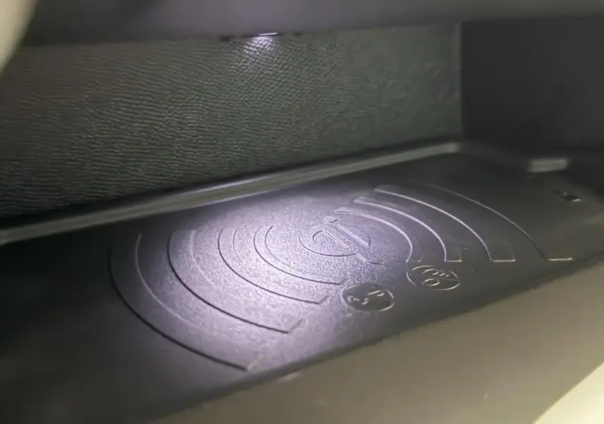 Gros plan sur le chargeur sans fil noir dans l'habitacle de la Peugeot 308 rouge, version BlueHDi 130 AUTO8 ALLURE.