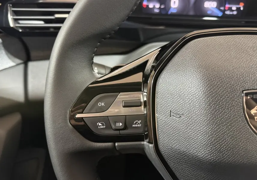 Gros plan sur le volant cuir multifonctions côté gauche du Peugeot 308 2025, avec commandes de régulateur et assistant.