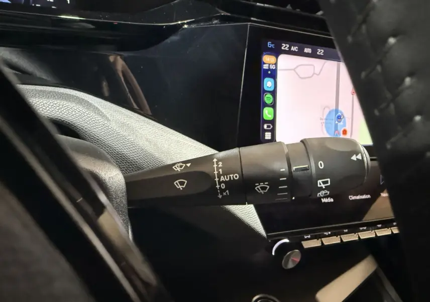 Gros plan sur la commande d’essuie-glace côté gauche du tableau de bord d’une Peugeot 308 2025 avec écran tactile allumé.