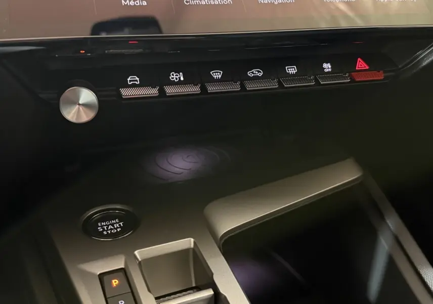 Gros plan sur la console centrale noire de la Peugeot 308 2025 avec boutons tactiles, bouton start/stop et rangement.