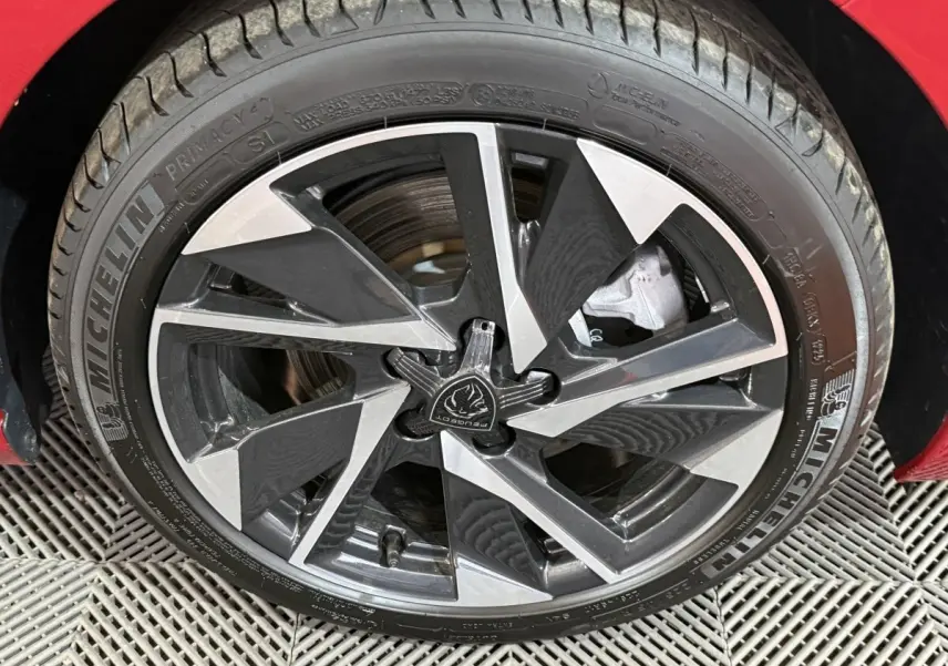 Gros plan sur la jante alliage bicolore et pneu Michelin d’une Peugeot 308 rouge, côté avant droit.