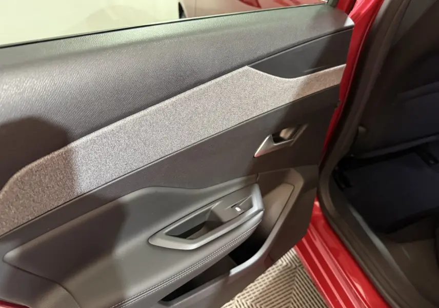 Vue rapprochée de la porte arrière droite rouge d’une Peugeot 308 2025 avec garniture noire et grise.