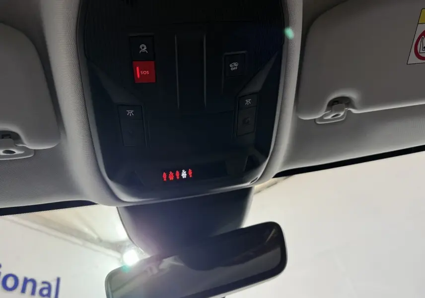 Vue intérieure du plafond avant de la Peugeot 308 rouge, avec commandes SOS et éclairage au-dessus du rétroviseur central.