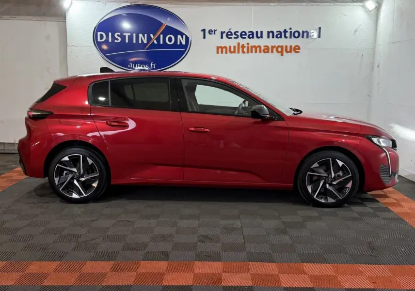 Profil droit d'une Peugeot 308 BlueHDi 130 AUTO8 Allure rouge, stationnée en intérieur avec jantes alliage distinctives.