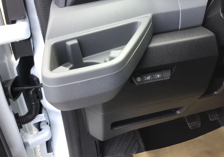 Détail de la porte côté conducteur du Renault Master blanc 2025, avec poignée intégrée et commandes de réglage des phares.