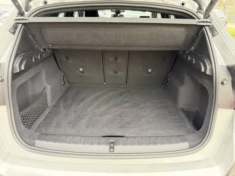 Coffre ouvert vu de l'arrière d'un BMW X1 XDrive20d 2025 couleur Spacesilber métal, intérieur noir avec filet de rangement.