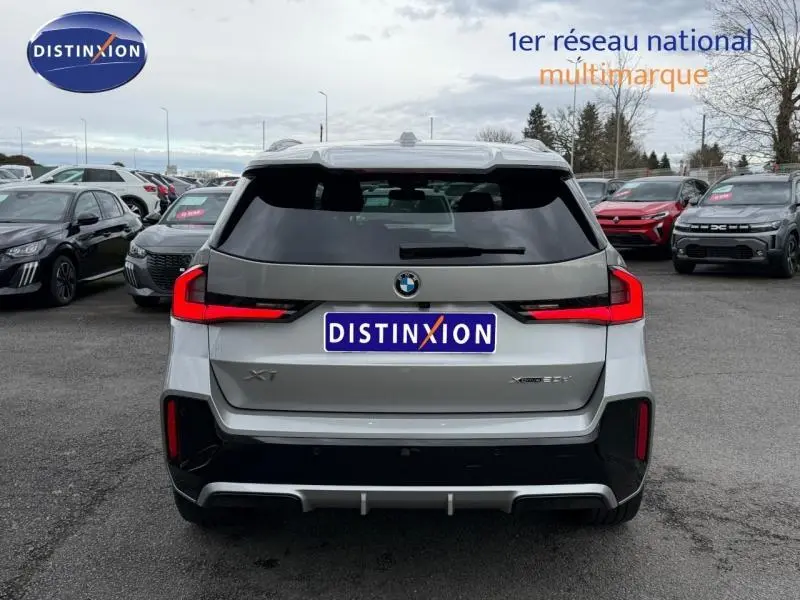 Vue arrière d'une BMW X1 xDrive20d M Sport 2025 en Spacesilber métal, avec feux LED distinctifs et toit noir.