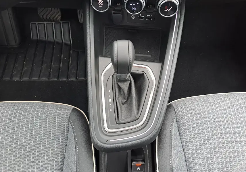 Vue plongeante sur la console centrale de la Renault Clio V hybride, avec levier de boîte auto et sièges tissu gris.