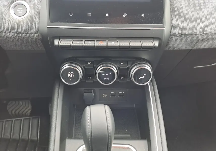 Vue rapprochée du tableau de bord de la Renault Clio V 2025, montrant les commandes de climatisation et la console centrale noire.