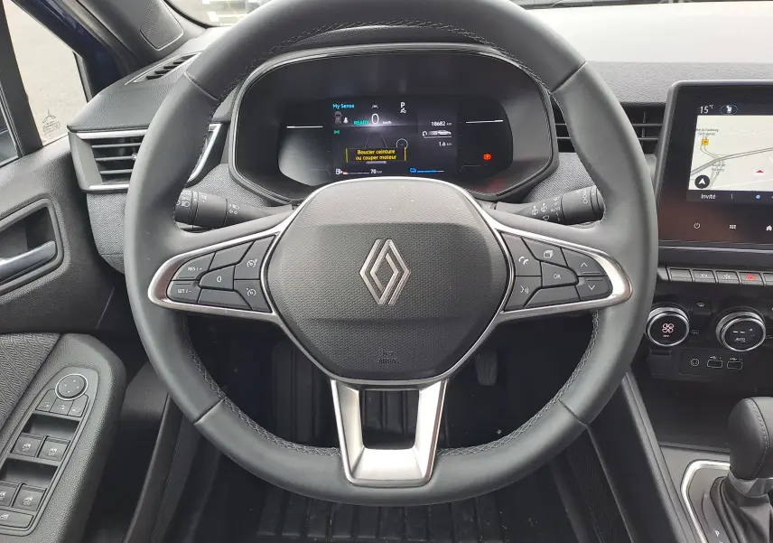 Vue frontale du volant noir de la Renault Clio V avec tableau de bord numérique et écran tactile central visible.