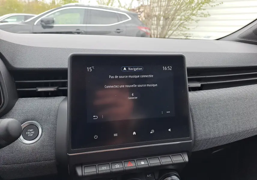 Vue intérieure centrée sur l'écran tactile et tableau de bord gris texturé de la Renault Clio V hybride 2025.