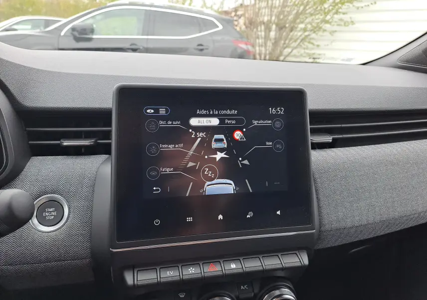 Vue intérieure centrée sur l'écran tactile du tableau de bord de la Renault Clio V bleu iron metal avec commandes visibles.