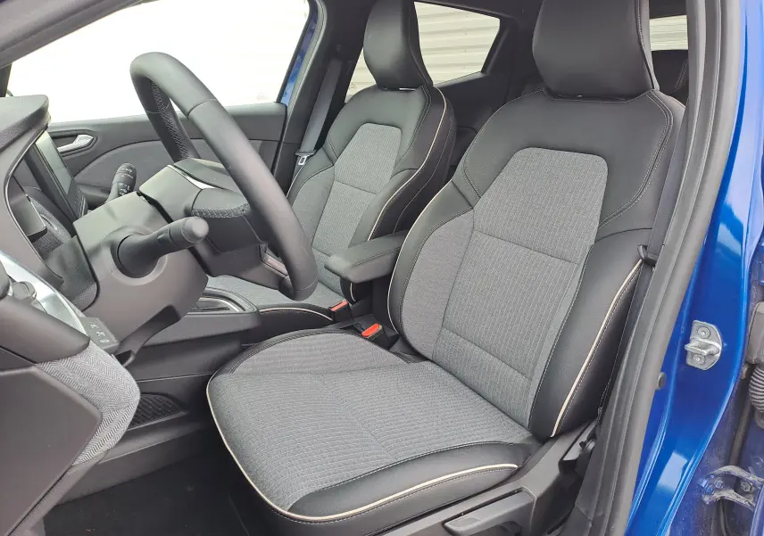 Vue intérieure côté conducteur de la Renault Clio V bleu iron metal, sièges tissu gris avec surpiqûres contrastées.