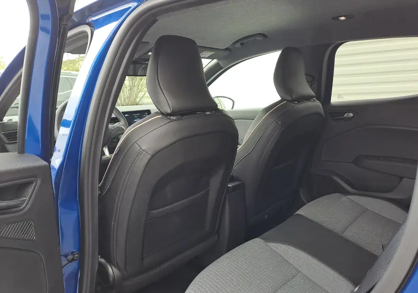 Vue intérieure arrière de la Renault Clio V bleu iron metal, montrant les sièges avant en cuir noir et la banquette arrière tissu gris.