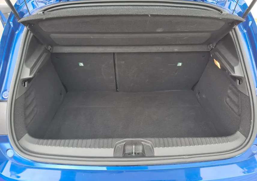 Coffre ouvert vu de dessus d'une Renault Clio V bleu iron metal, montrant un espace de rangement propre et spacieux.