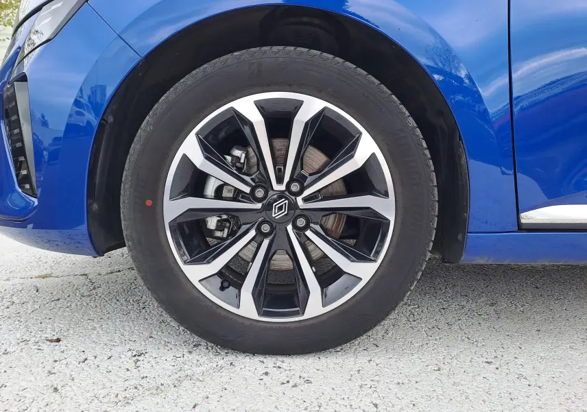 Gros plan sur la roue avant droite d'une Renault Clio V bleu iron metal avec jante alliage bicolore moderne.