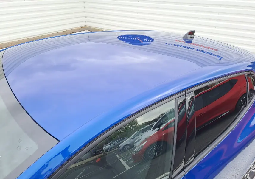 Vue en plongée du toit bleu iron metal d'une Renault Clio V hybride avec antenne requin et vitres teintées.
