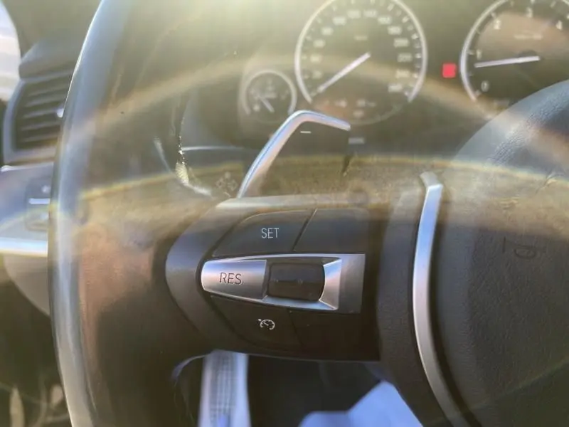 Gros plan sur le volant noir du BMW X4 30DA X DRIVE 2016, avec commandes de régulateur de vitesse visibles.