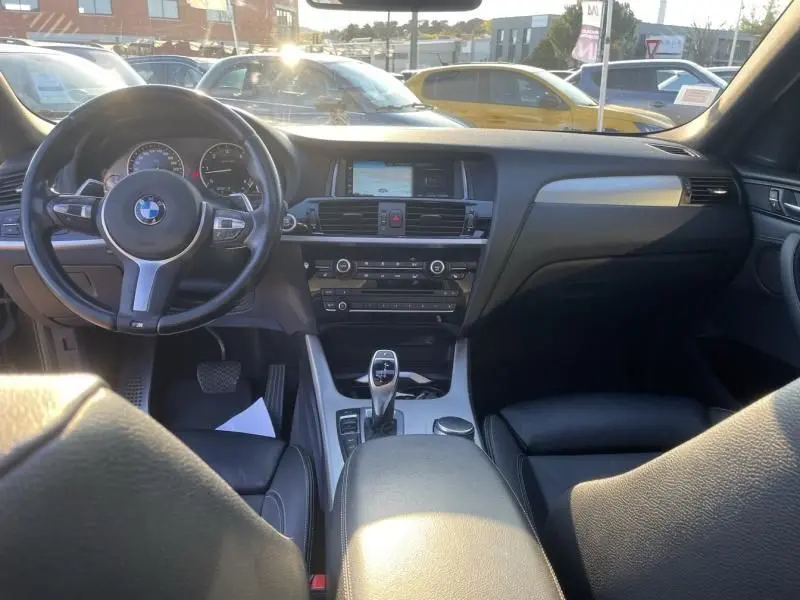 Vue intérieure du tableau de bord et volant de la BMW X4 30DA X DRIVE noir métal, avec console centrale et écran multimédia.