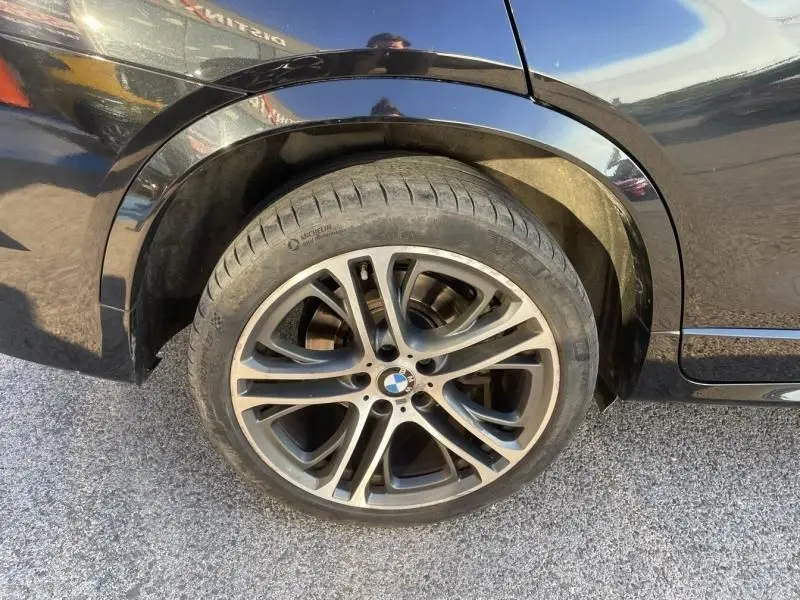 Gros plan sur la roue arrière droite d’un BMW X4 noir métal 2016 avec jante alliage M Sport et pneu Michelin.