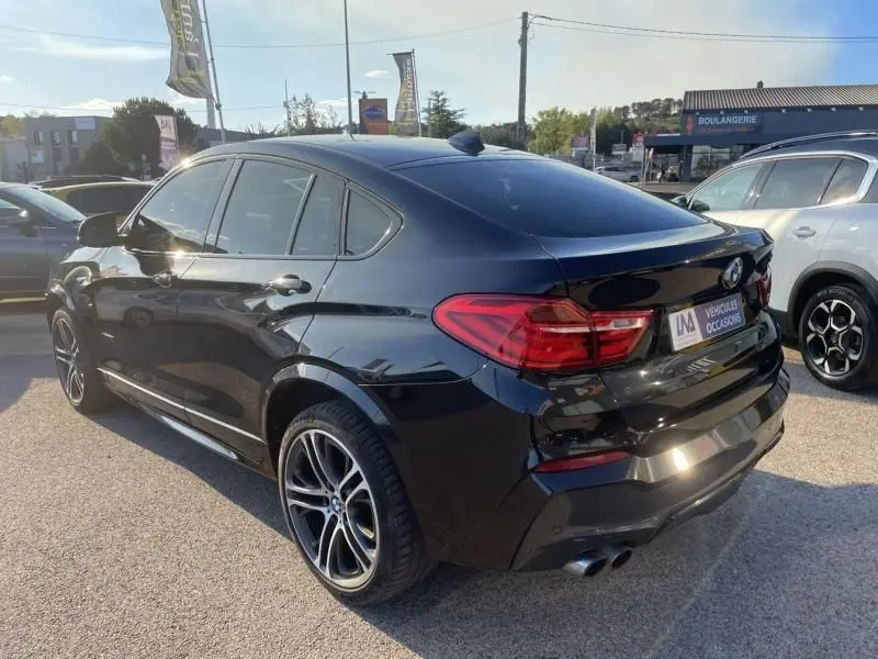 BMW X4 30DA X DRIVE noir métal vue 3/4 arrière droit, avec jantes sport et double sortie d’échappement visible.