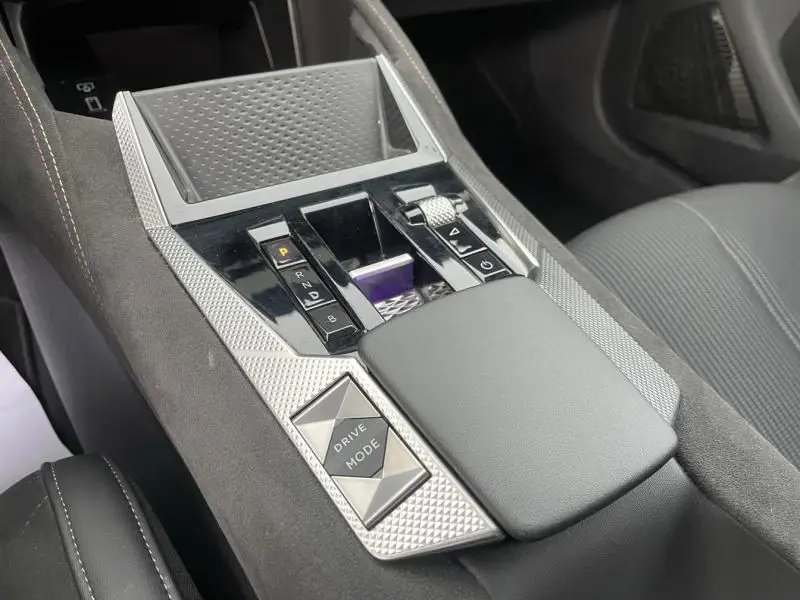 Console centrale en gros plan de la DS4 hybride gris 2023, mettant en valeur les commandes de boîte auto et le bouton Drive Mode.