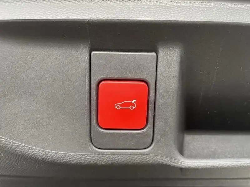 Bouton rouge de déverrouillage du coffre sur un DS4 gris hybride rechargeable 2023, vue en gros plan intérieur.