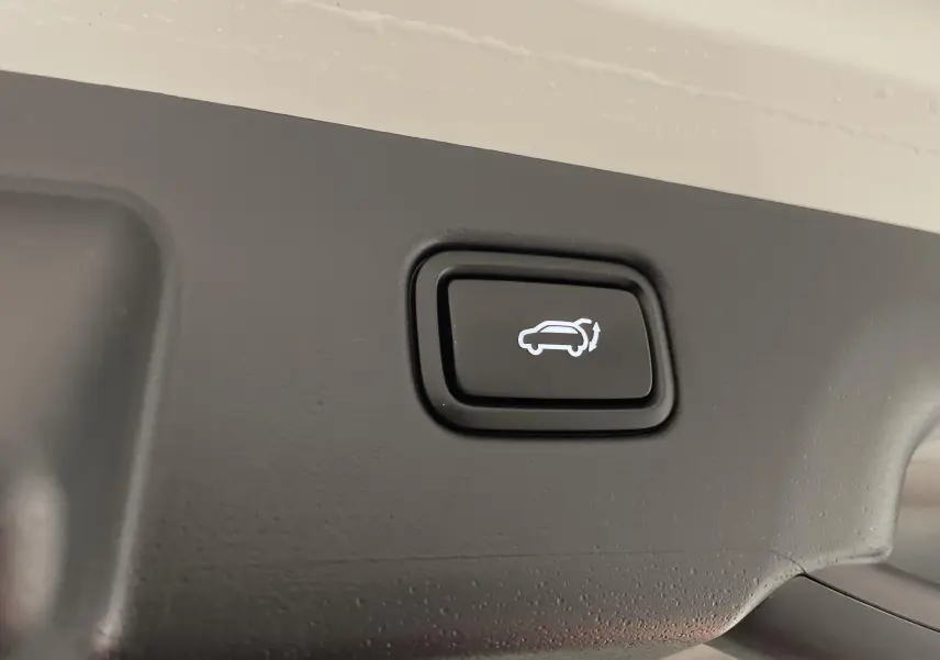Bouton d'ouverture électrique du hayon sur le coffre intérieur d'un Kia Niro blanc hybride 2025.