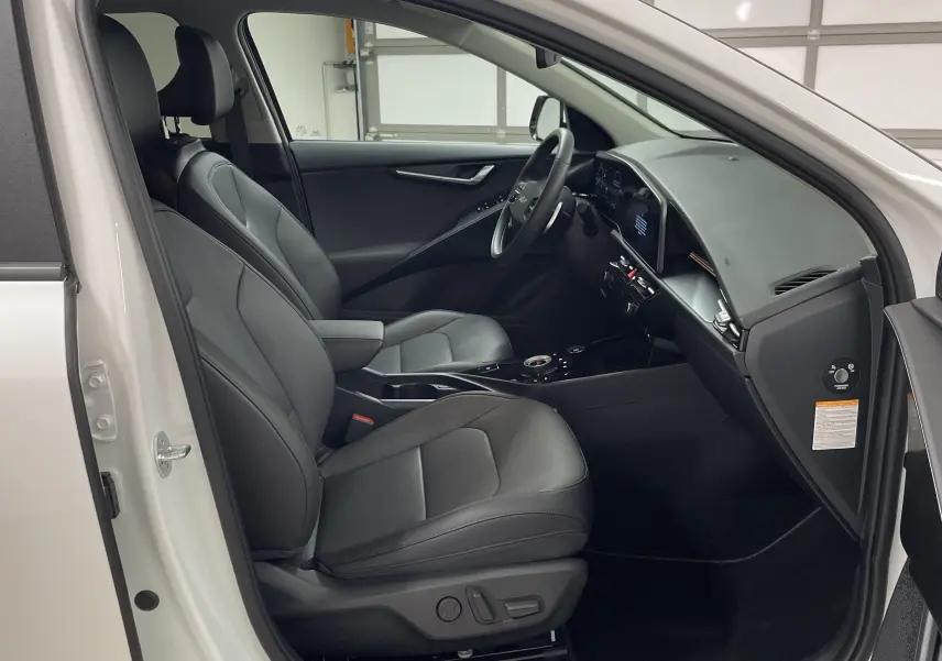 Intérieur noir du Kia Niro 2025 vu côté conducteur avec tableau de bord moderne et sièges en cuir.