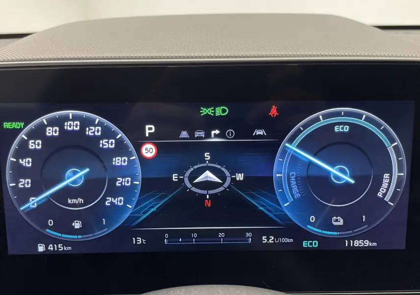 Tableau de bord numérique du Kia Niro blanc 2025, affichant vitesse, autonomie, consommation et mode ECO.