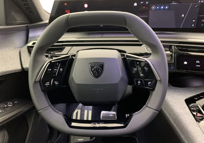 Volant compact cuir noir perforé avec badge GT et tableau de bord numérique du Peugeot 3008 Hybrid 2025, vue de face intérieure.