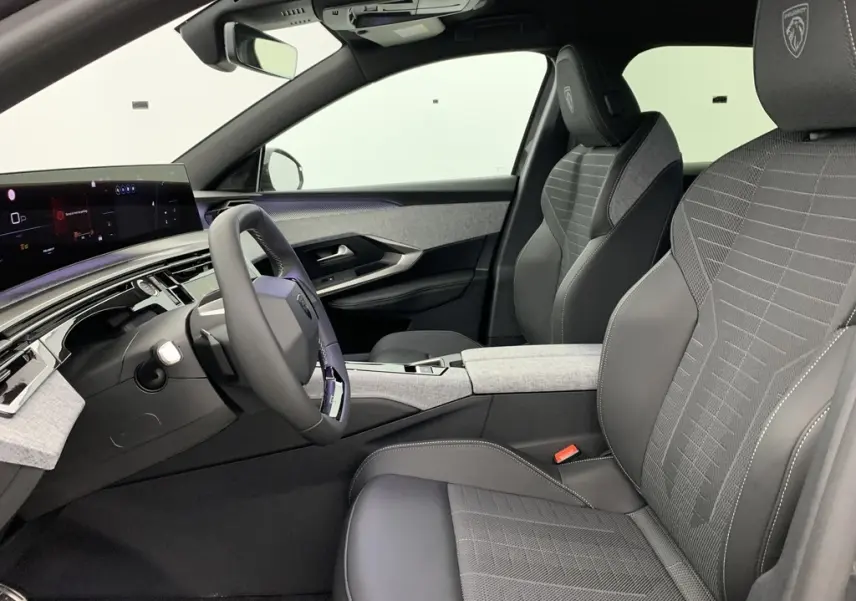 Vue intérieure côté conducteur du Peugeot 3008 Hybrid 145 GT avec sellerie tissu gris et volant compact cuir noir.