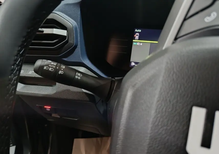 Gros plan sur la manette de clignotants et partie gauche du tableau de bord bleu foncé du Dacia Bigster 2025 gris foncé.