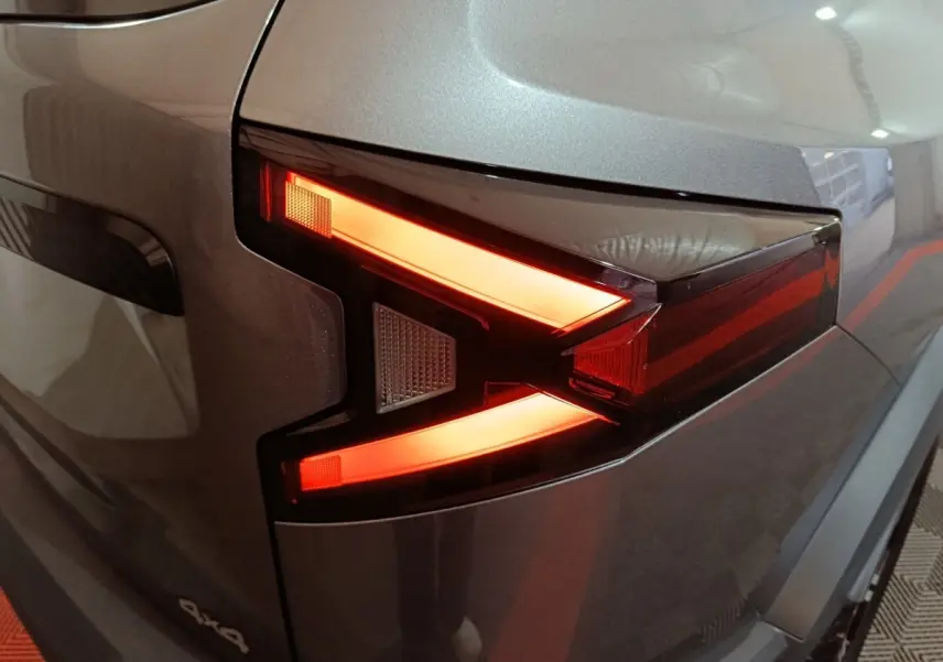 Gros plan sur le feu arrière droit allumé du Dacia Bigster gris foncé 2025 avec logo 4x4 visible.