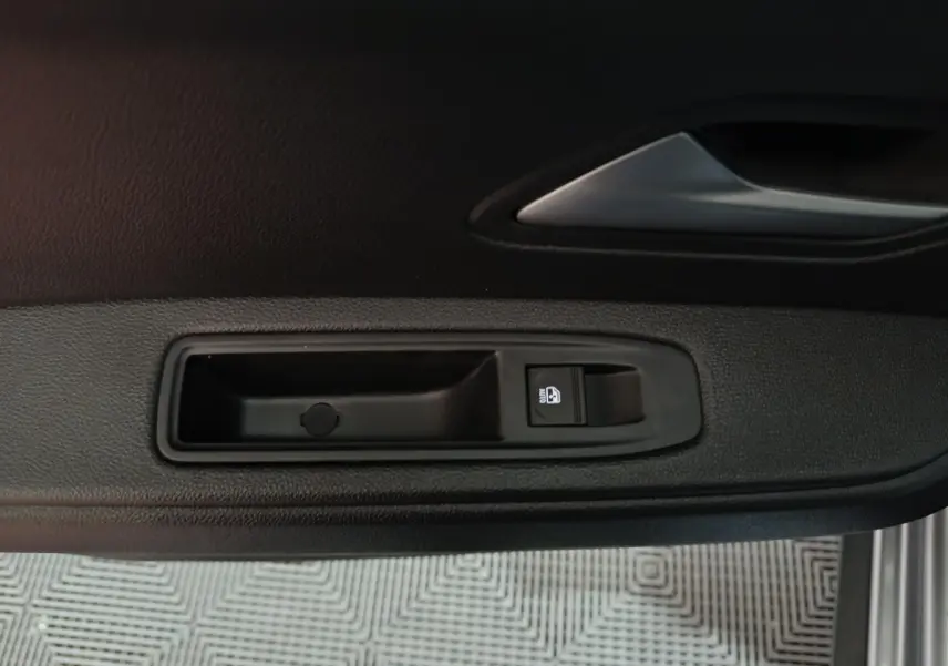 Gros plan sur la commande de lève-vitre côté conducteur du Dacia Bigster gris foncé, intérieur noir.