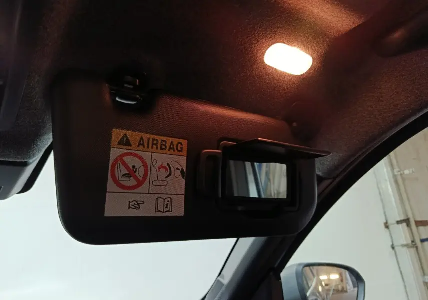 Détail du pare-soleil côté conducteur avec miroir ouvert et avertissement airbag dans un Dacia Bigster gris foncé.