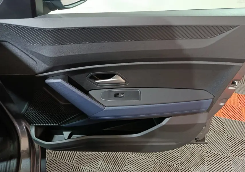 Vue intérieure de la porte avant gauche gris foncé du Dacia Bigster avec poignée argentée et insert bleu.