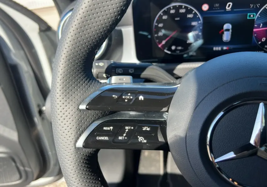 Gros plan sur le volant cuir perforé de la Mercedes Classe A 200D BVA Exclusive Design avec commandes multifonctions visibles.