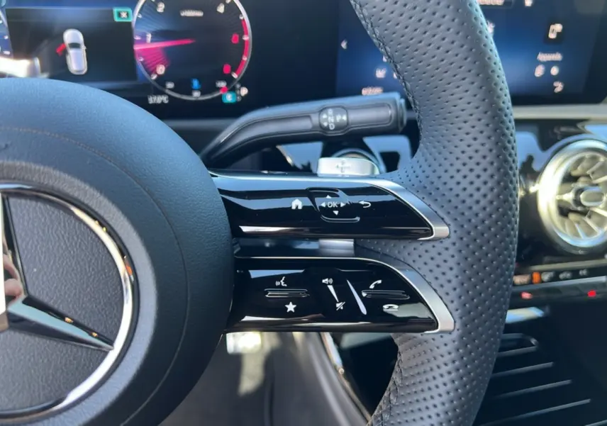 Gros plan sur le volant cuir perforé de la Mercedes Classe A 200D 2026, avec commandes multifonctions et tableau de bord numérique.