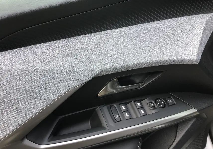 Gros plan sur la garniture grise et les commandes de porte côté conducteur du Peugeot 3008 1.2 Hybrid 145 Allure 2026.