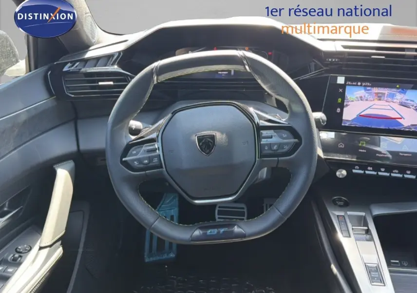 Vue intérieure centrée sur le volant cuir noir et le tableau de bord digital de la Peugeot 308 Hybrid 145ch GT 2026.