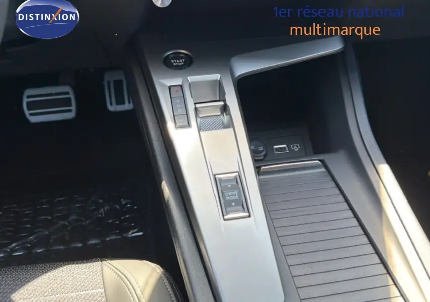 Vue rapprochée de la console centrale de la Peugeot 308 Hybrid 145ch GT 2026 avec levier de vitesses et bouton Drive Mode.