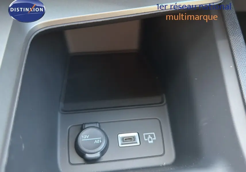 Gros plan intérieur sur la prise 12V et port USB dans le rangement central de la Peugeot 308 Hybrid 145ch GT noir perle métal.