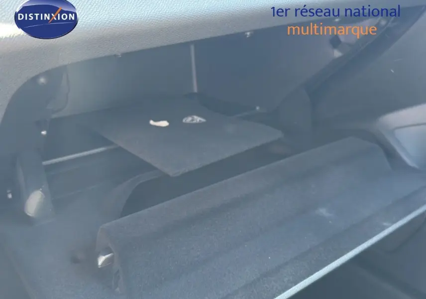 Coffre ouvert de la Peugeot 308 Hybrid 145ch GT 2026 en noir perle métal, montrant la moquette et un rangement intérieur.