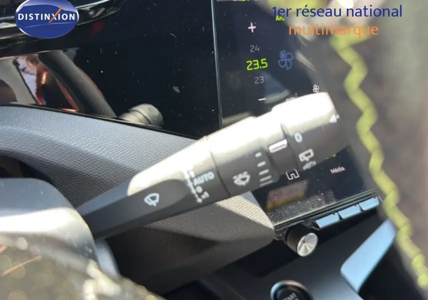 Gros plan sur la commande d’essuie-glace à gauche du volant d’une Peugeot 308 Hybrid noir perle métal, intérieur moderne.