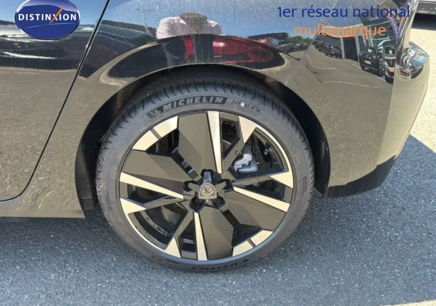 Gros plan sur la roue arrière droite d'une Peugeot 308 Hybrid 145ch GT noir perle métal avec jante moderne bicolore.