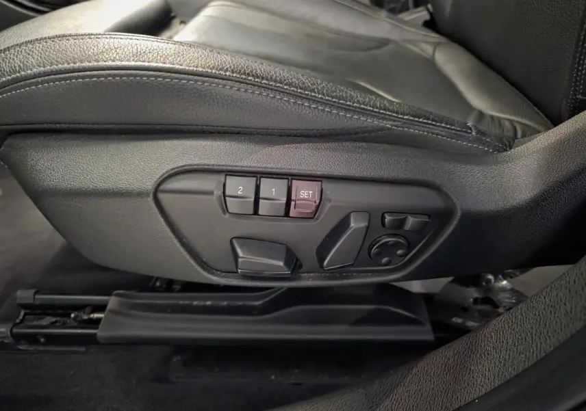 Détail des commandes de réglage électrique du siège conducteur en cuir noir dans une BMW X2 M Sport blanche.