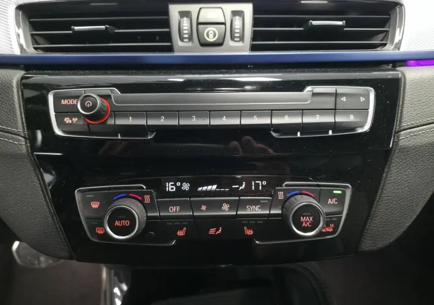 Panneau de commande central noir brillant avec climatisation bi-zone et réglages multifonctions dans BMW X2 blanc 2023.