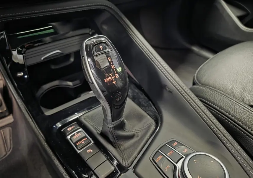 Gros plan sur la console centrale noire du BMW X2 M Sport 2023, avec levier de vitesses automatique et commandes de mode de conduite.