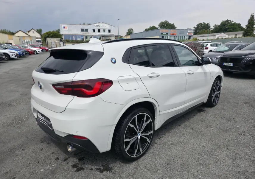 BMW X2 sDrive 18d M Sport blanc vue 3/4 arrière droit avec jantes alliage 20 pouces et toit noir panoramique.